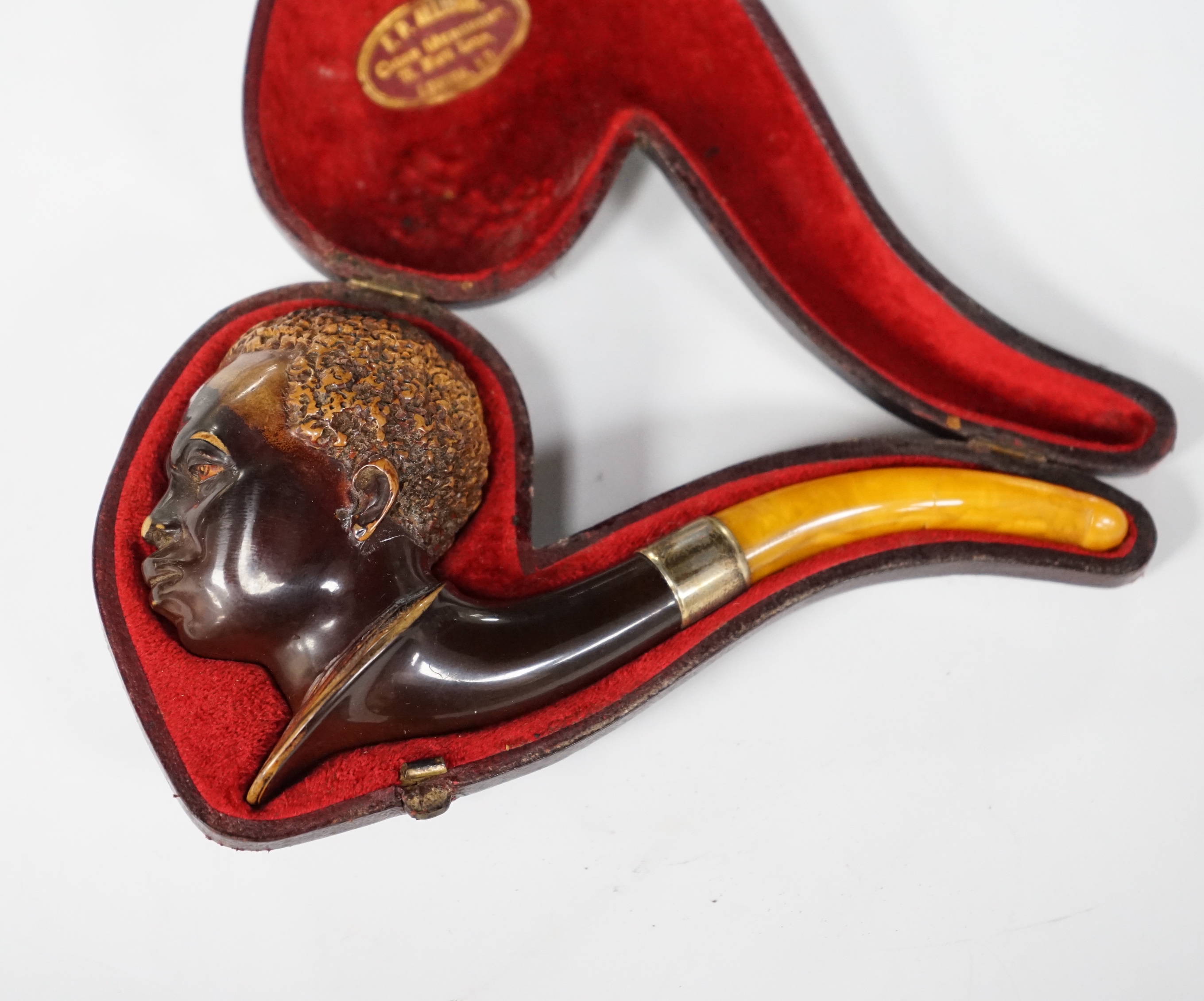 A cased Meerschaum pipe with a bowl modelled as a Nubian man’s head with metal mount and amber mouthpiece, 14cm long